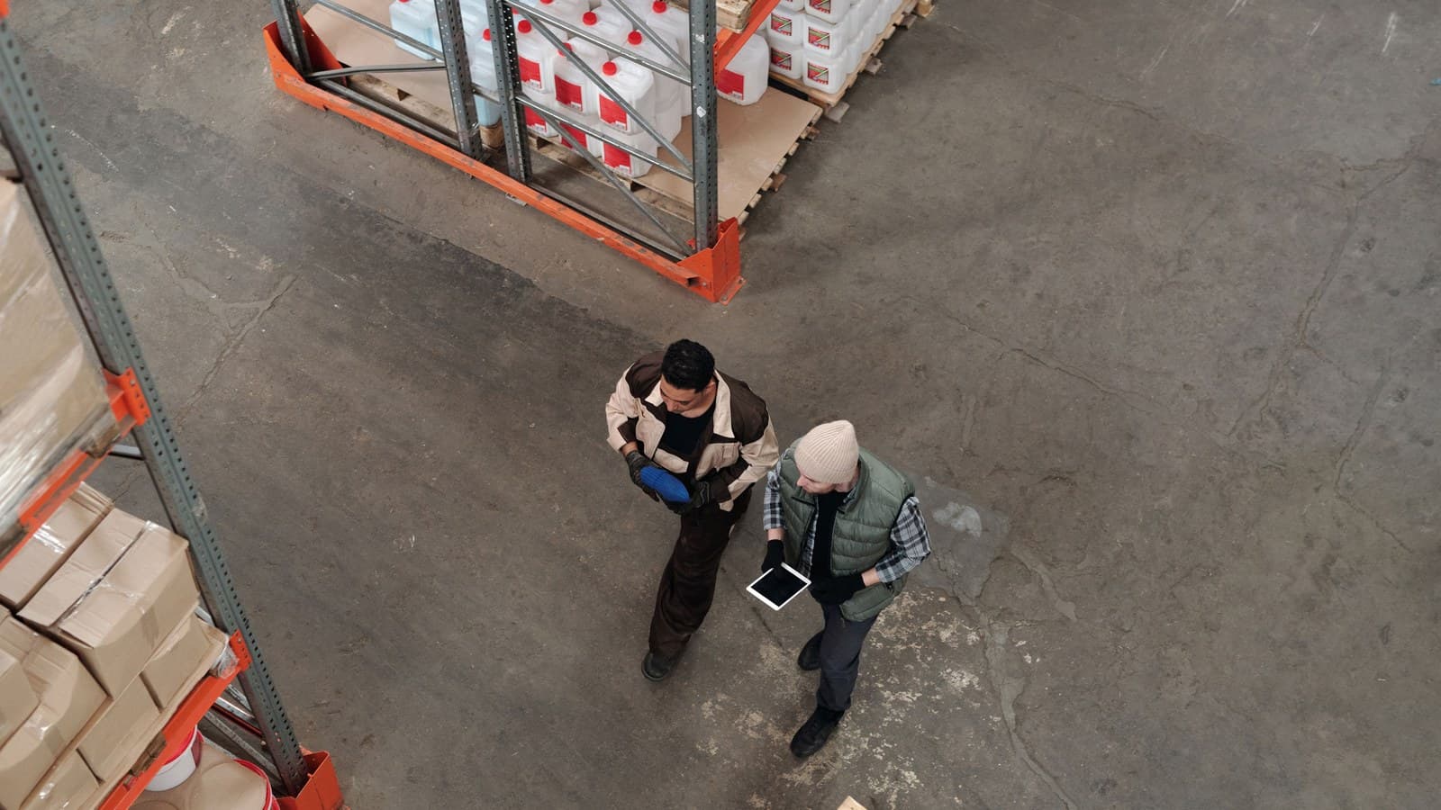 Two warehouse coworkers coordinate inventory using a tablet