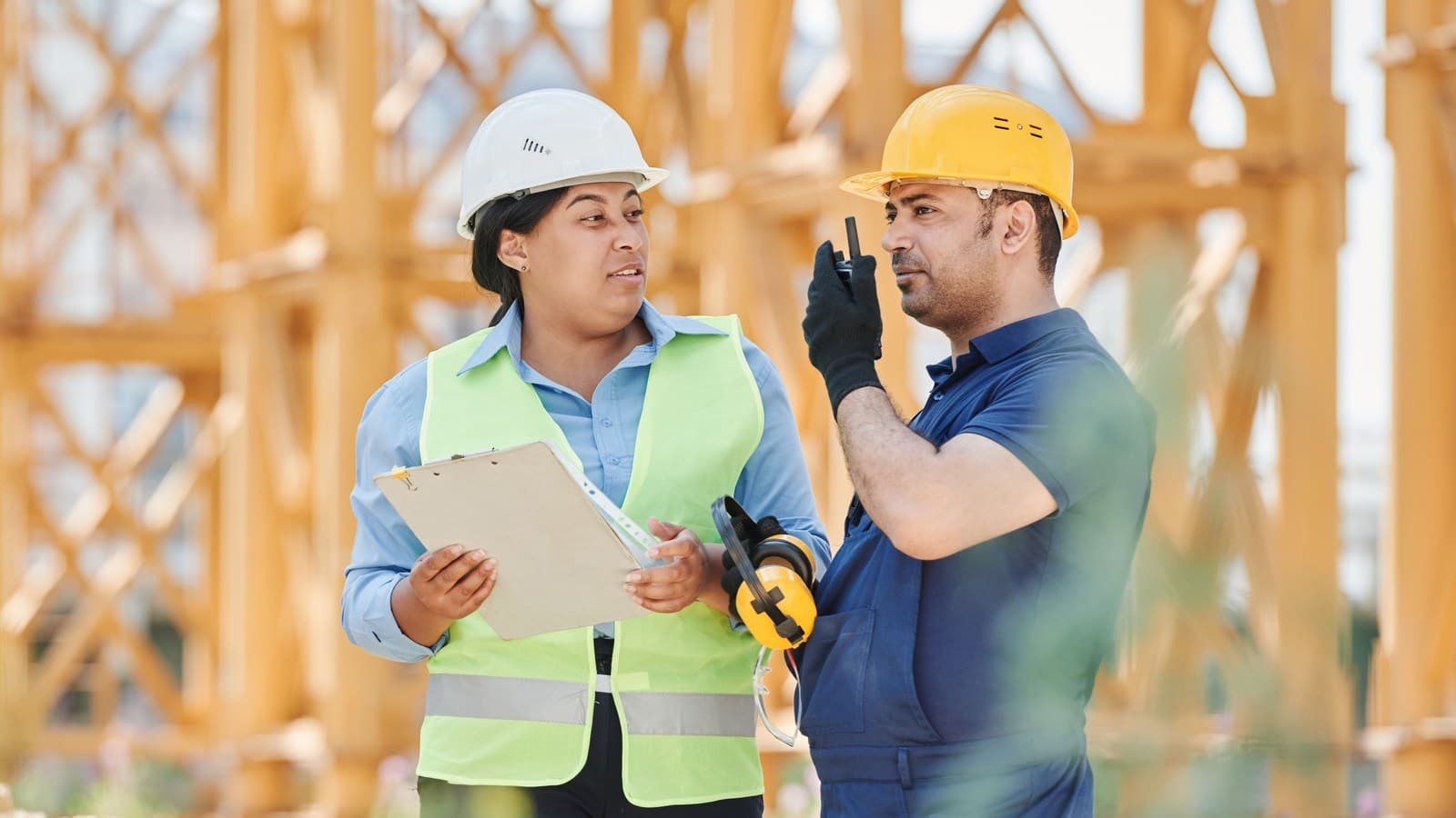 Two construction professionals review project plans at the worksite