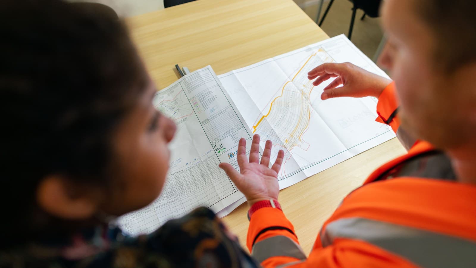 Engineers review technical plans together at a worktable